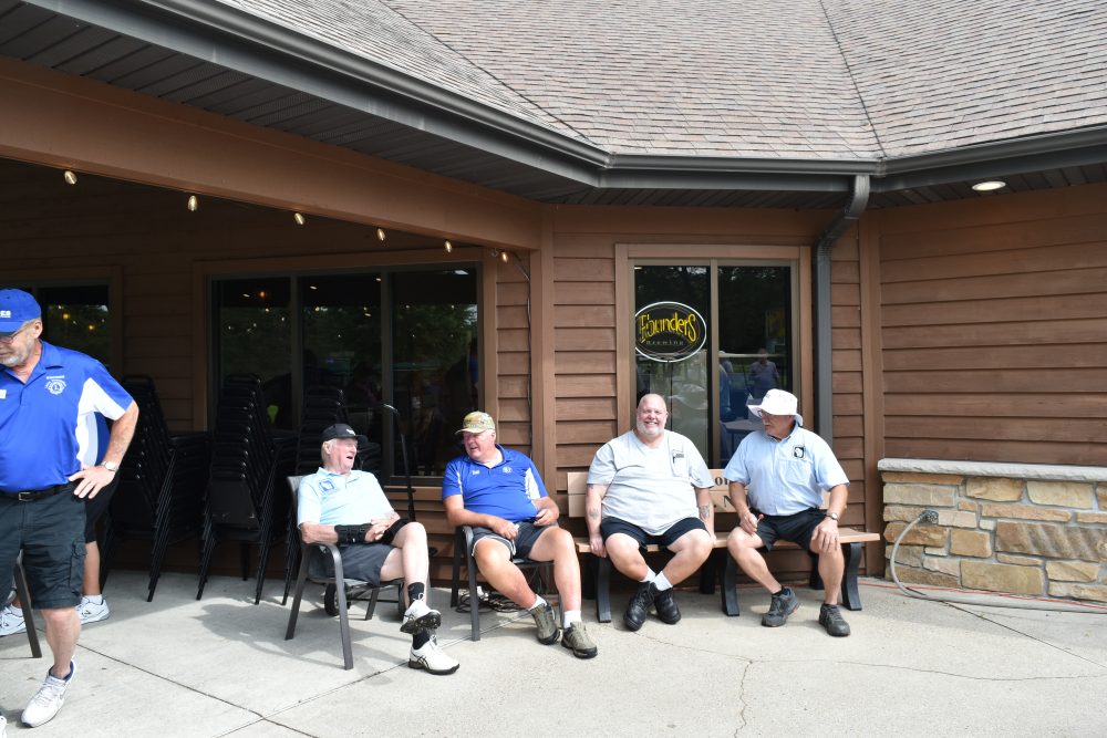 Four individuals sitting in chairs waiting for the start of the golf outing